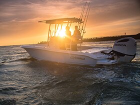 A boat using a Honda outboard on the water at sunset